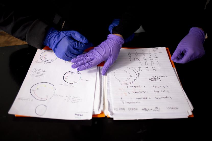 Two students flip through research notes in a lab. 