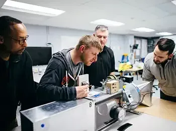 four students working on device in a lab