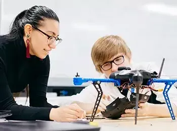 two people looking at a drone on a table